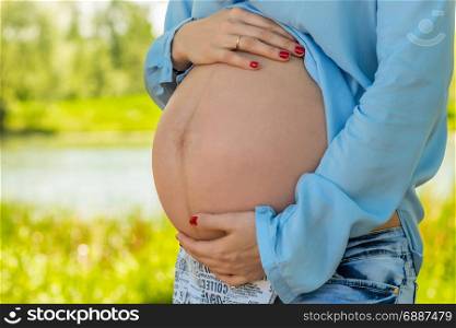 Beautiful big belly of a pregnant woman close-up, shooting in the park