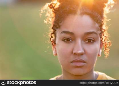 Beautiful biracial mixed race African American teenager teen girl young woman sad or depressed outside backlit at sunset or sunrise