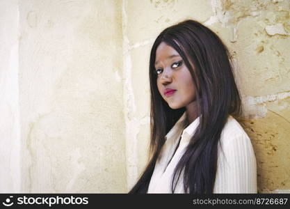 Beautiful black African woman model posing against a wall looking directly at the camera