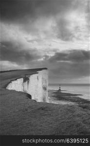 Beautiful black and white landscape image of Beachy Headt lighthouse on South Downs National Park during stormy sky