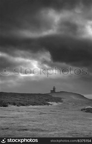 Beautiful black and white landscape image of Belle Tout lighthouse on South Downs National Park during stormy sky