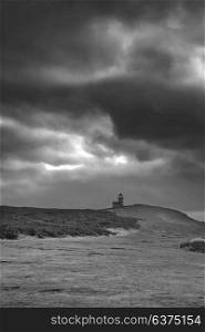 Beautiful black and white landscape image of Belle Tout lighthouse on South Downs National Park during stormy sky