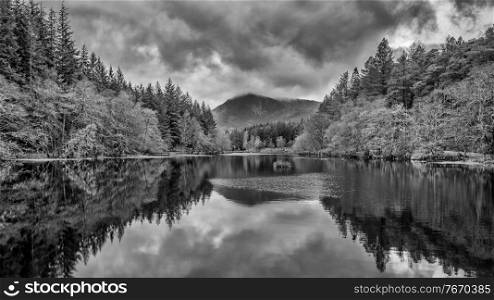Beautiful  black and white landscape image of Glencoe Lochan with Pap of Glencoe in the distance on a Winter’s evening