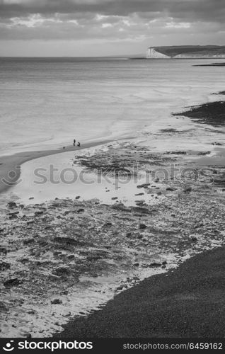 Beautiful black and white long exposure landscape image of low tide beach with rocks at sunrise