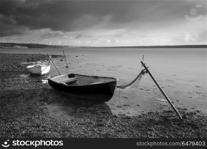 Beautiful black and white sunset landscape image of boats moored. Beautiful black and white sunset landscape image of boats moored in Fleet Lagoon in Dorset England