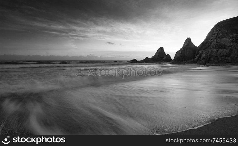 Beautiful black and white sunset landscape image of Westcombe Beach in Devon England 
