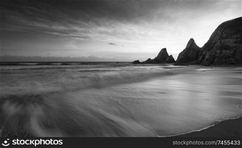 Beautiful black and white sunset landscape image of Westcombe Beach in Devon England