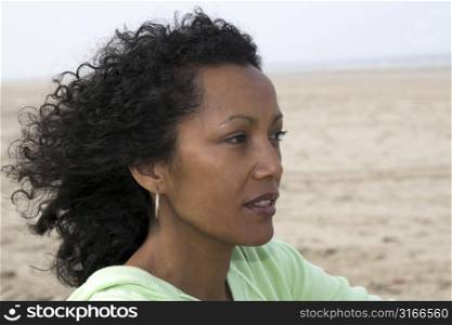 Beautiful black woman by the seaside enjoying the wind on her face