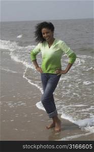 Beautiful black woman having fun on the beach standing by the waterline