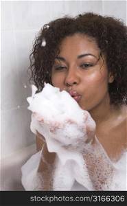 Beautiful black woman in a bathtub blowing bubbles