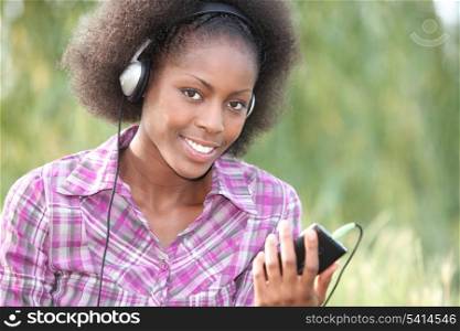 beautiful black woman listening music in the park