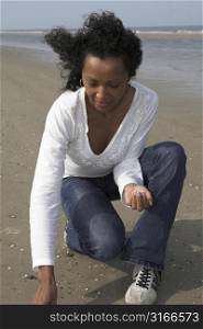 beautiful black woman looking for shells on the beach