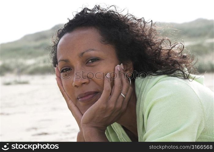 Beautiful black woman lying on the beach with the wind in her hair