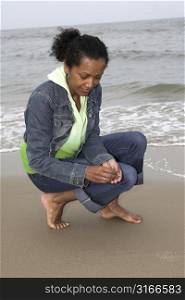 Beautiful black woman searching for shells on the beach