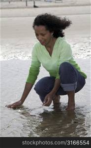 Beautiful black woman seeking shells in the shallow water during low tide