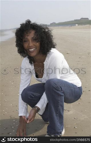 Beautiful black woman seeking shells on the beach