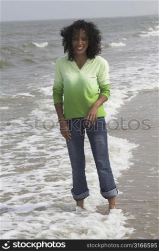 Beautiful black woman standing in the surf getting her jeans wet
