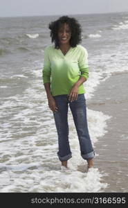 Beautiful black woman standing in the surf getting her jeans wet