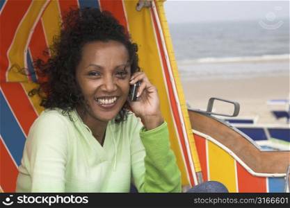 Beautiful black woman talking on the phone sitting in a beachchair on a windy day at the beach