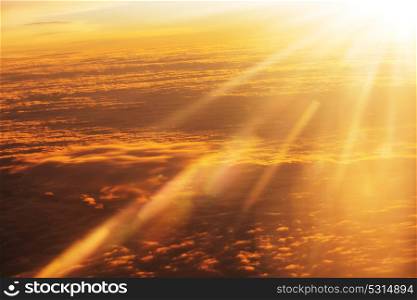 Beautiful blazing sunrise landscape above clouds. View from aircraft. Sunset and sunrise concept background.