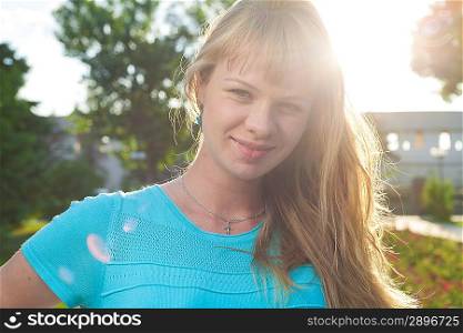 Beautiful blond early 30s woman head shot portrait outdoors sweeping hair back