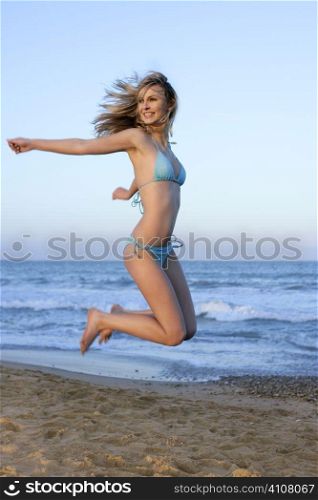Beautiful blond girl jumping bikini on the beach