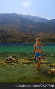 Beautiful blond girl standing in crystal clear water