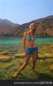 Beautiful blond girl stanging in crystal clear water