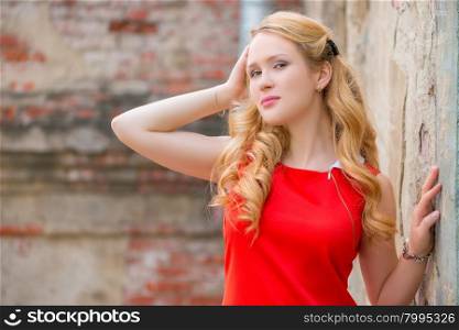 beautiful blond with curly hair posing near the wall
