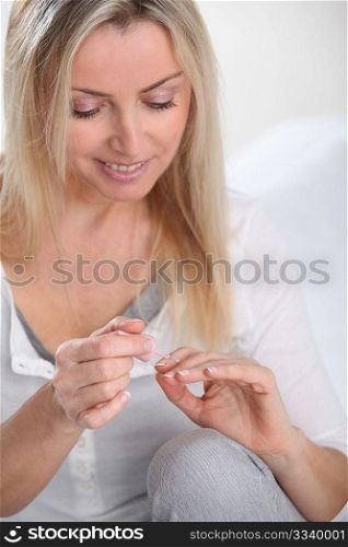Beautiful blond woman applying nail polish