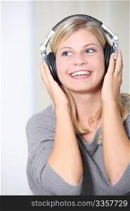 Beautiful blond woman at home with headphones on