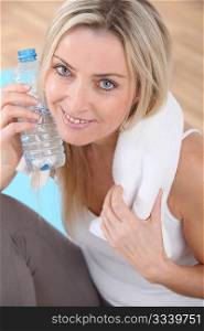 Beautiful blond woman drinking water after exercising