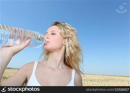 beautiful blond woman drinking water fom bottle