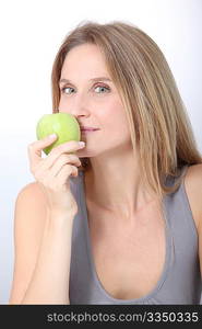 Beautiful blond woman eating green apple