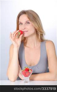Beautiful blond woman eating strawberries