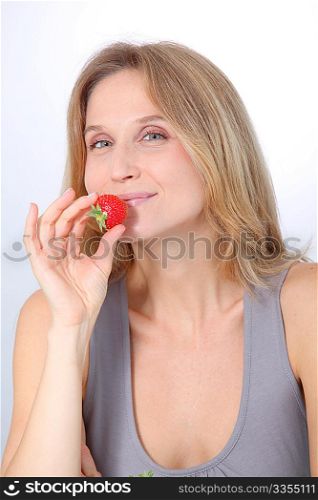 Beautiful blond woman eating strawberries