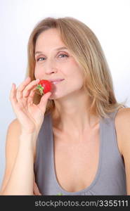 Beautiful blond woman eating strawberries