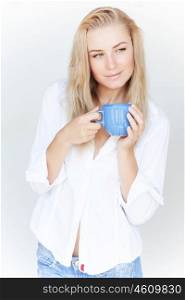 Beautiful blond woman holding blue coffee cup in hands isolated on white background, having morning drink at home