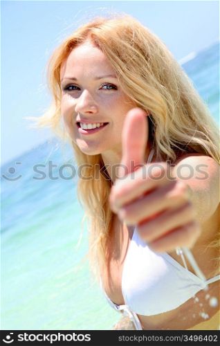 Beautiful blond woman in the sea showing thumbs up