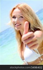 Beautiful blond woman in the sea showing thumbs up