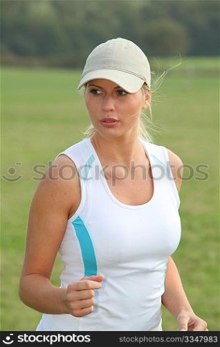 Beautiful blond woman jogging in countryside