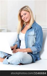 Beautiful blond woman laying on sofa with laptop computer
