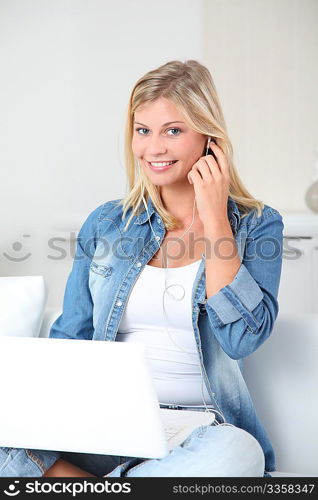 Beautiful blond woman listening to music on internet