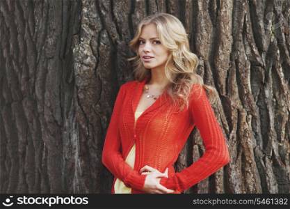 Beautiful blond woman posing on tree trunk background