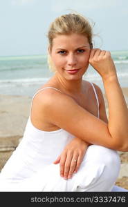 Beautiful blond woman practising yoga at the beach