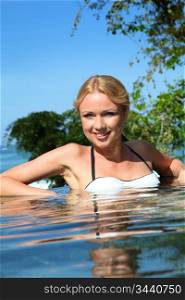Beautiful blond woman relaxing in resort pool