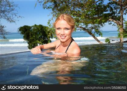 Beautiful blond woman relaxing in resort pool