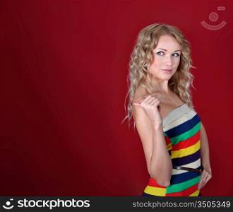 Beautiful blond woman showing thumb up on red background