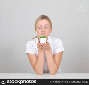 Beautiful blond woman smelling green plant