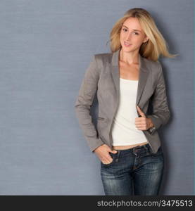 Beautiful blond woman standing on grey background